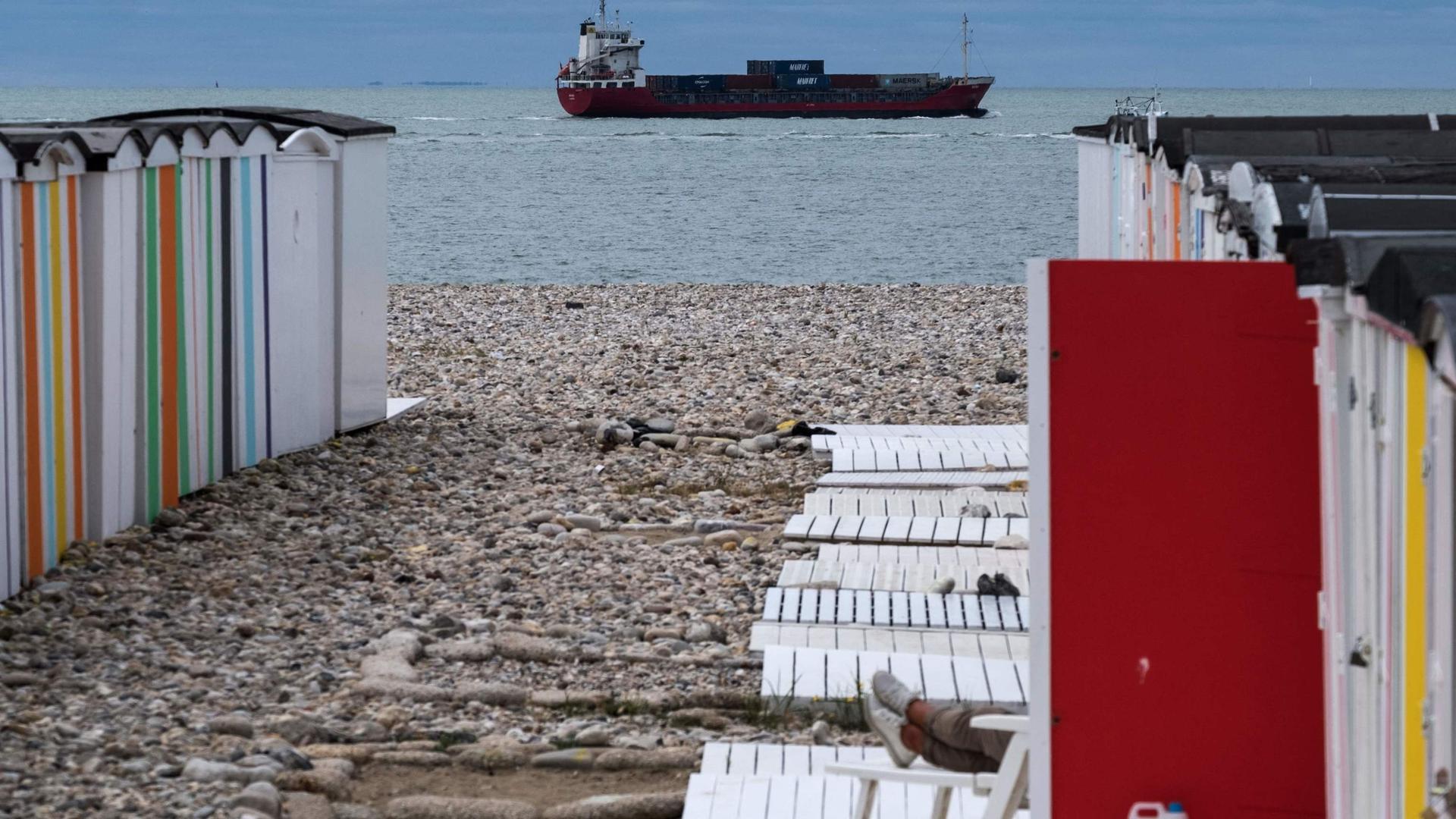 A container ship sails past multi-coloured beach huts in Le Havre, France
