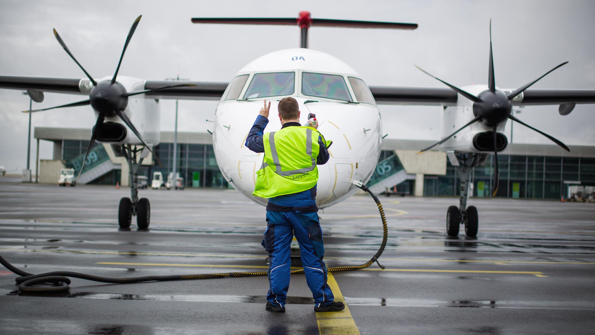 A Luxair worker signals to pilots aboard one of the airline's planes