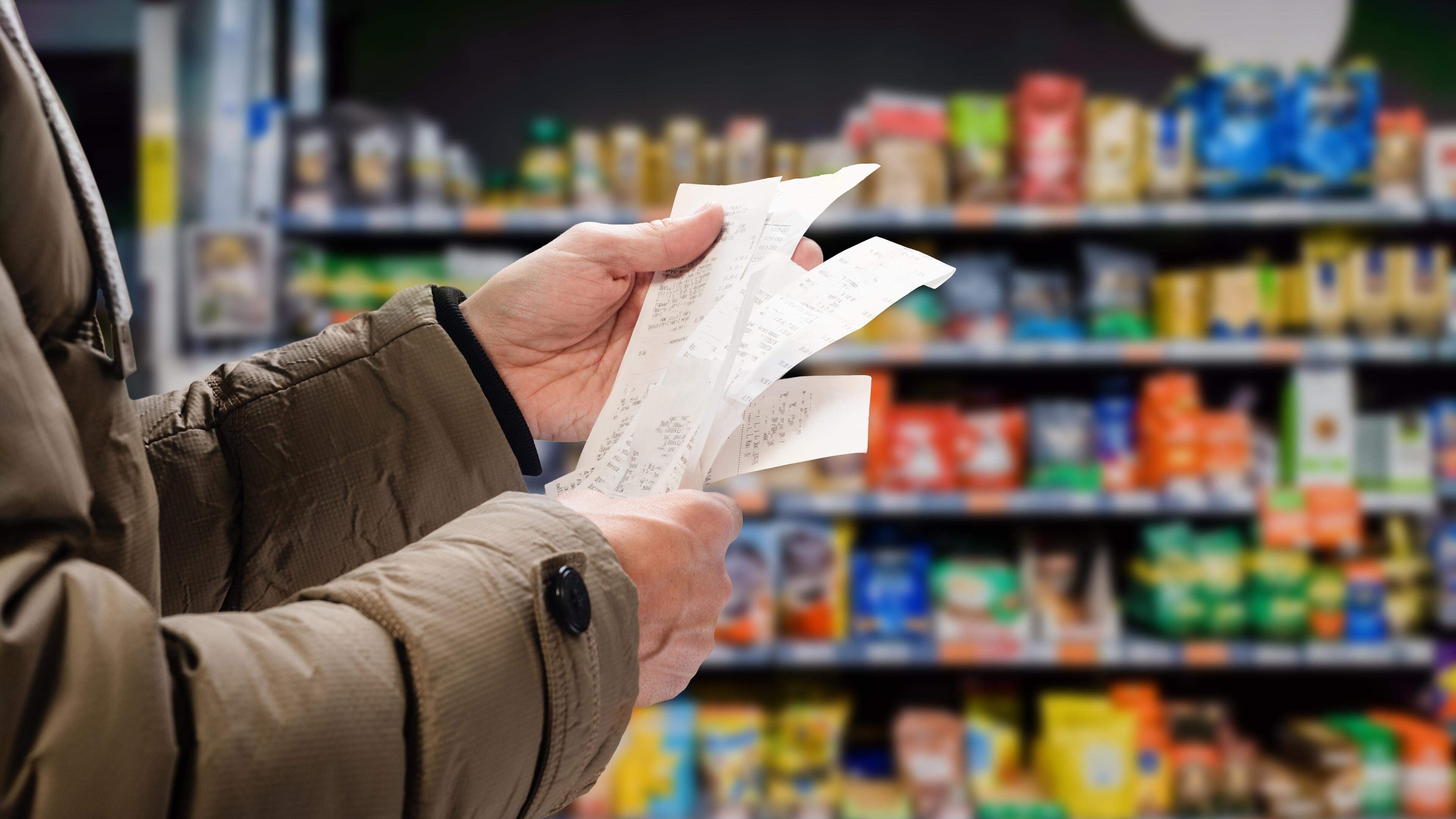 A stock photo of a man viewing receipts in supermarket.
