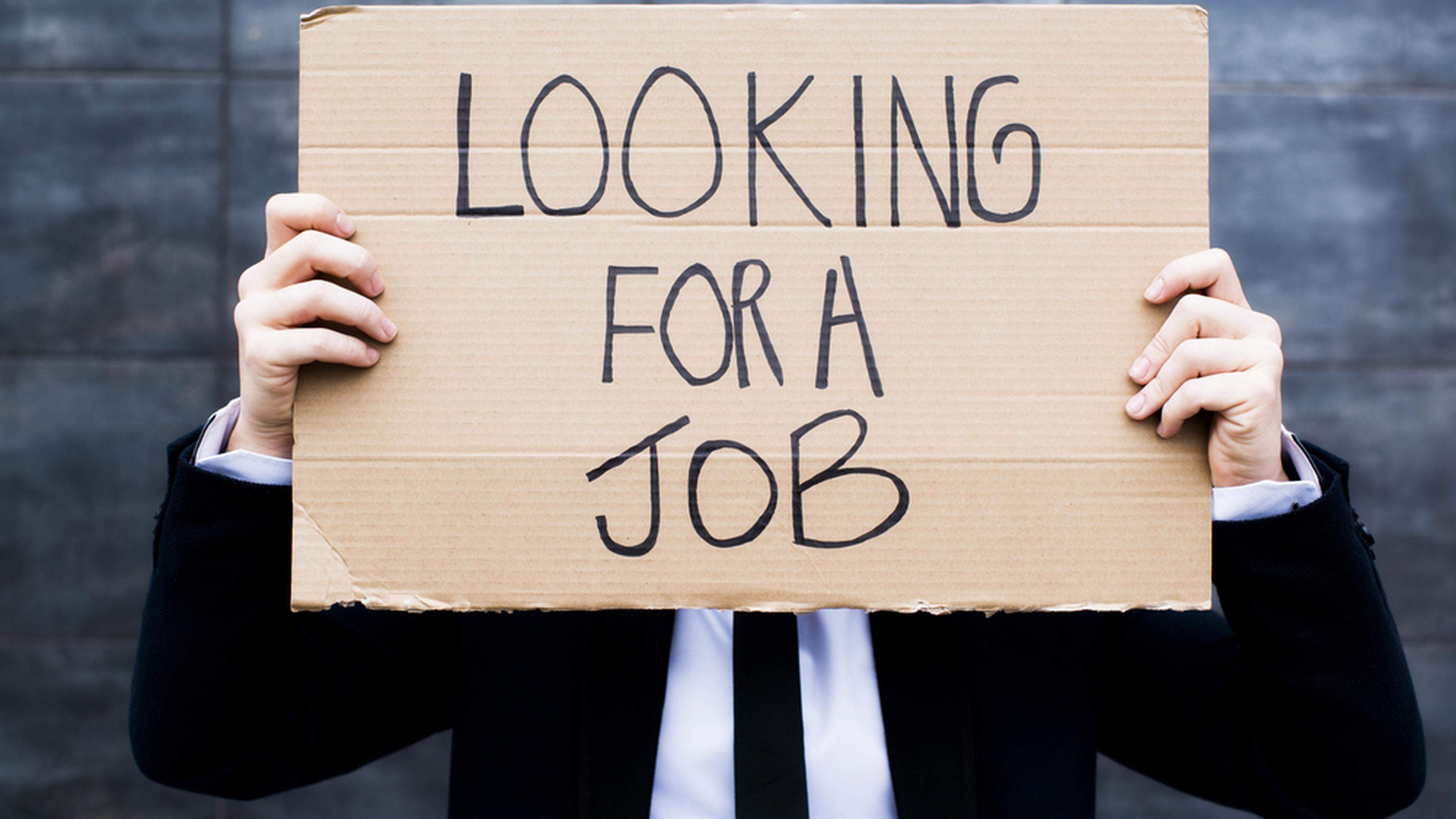 A person holding a sign “Looking for a job”