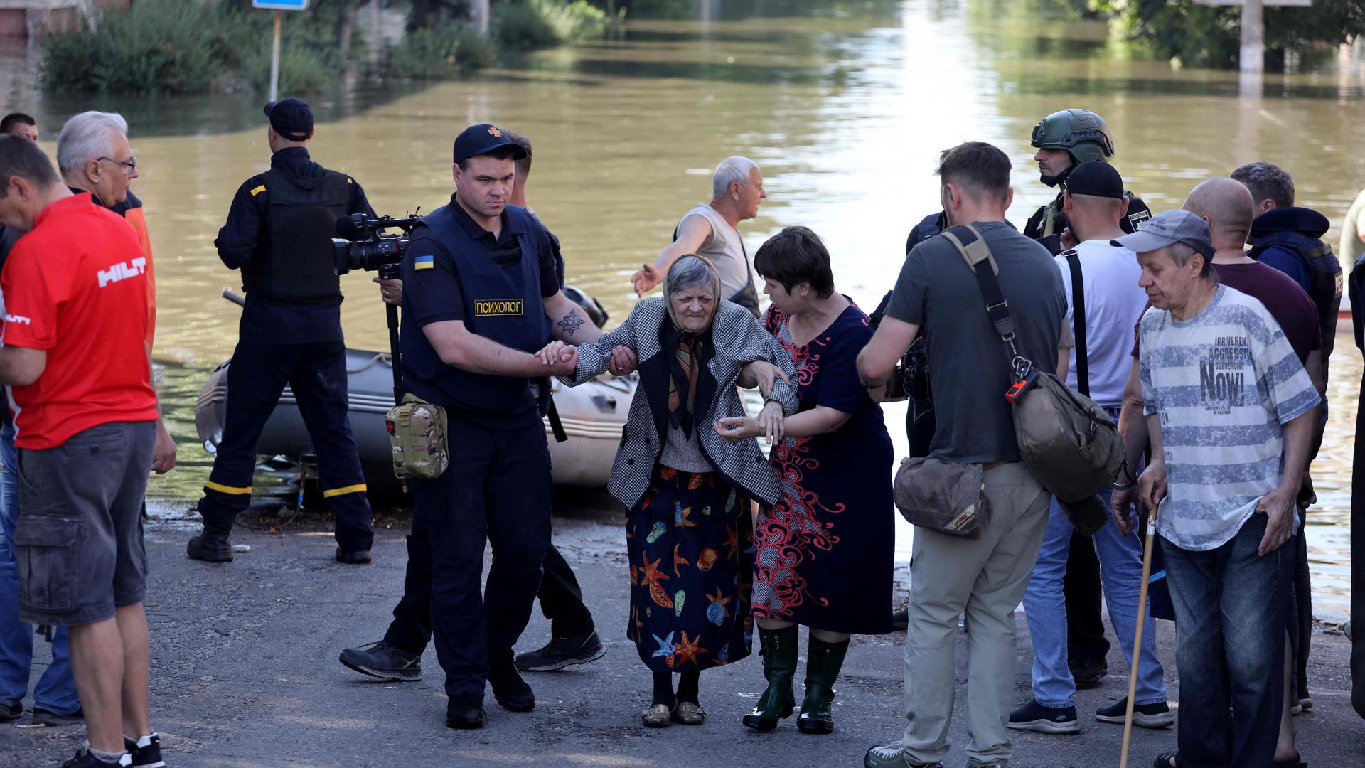 A policeman and a woman help evacuate an elderly local resident from a flooded area in Kherson on Wednesday following widespread flooding caused by damage to the Kakhovka hydroelectric power plant dam. 