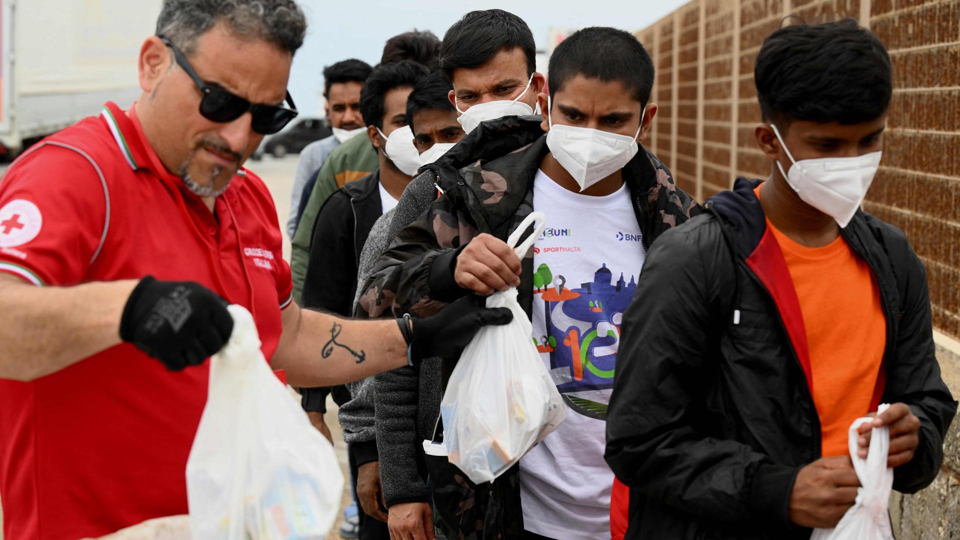 Migrants wait in line prior to board a boat at the port of the Italian island of Lampedusa on Thursday.