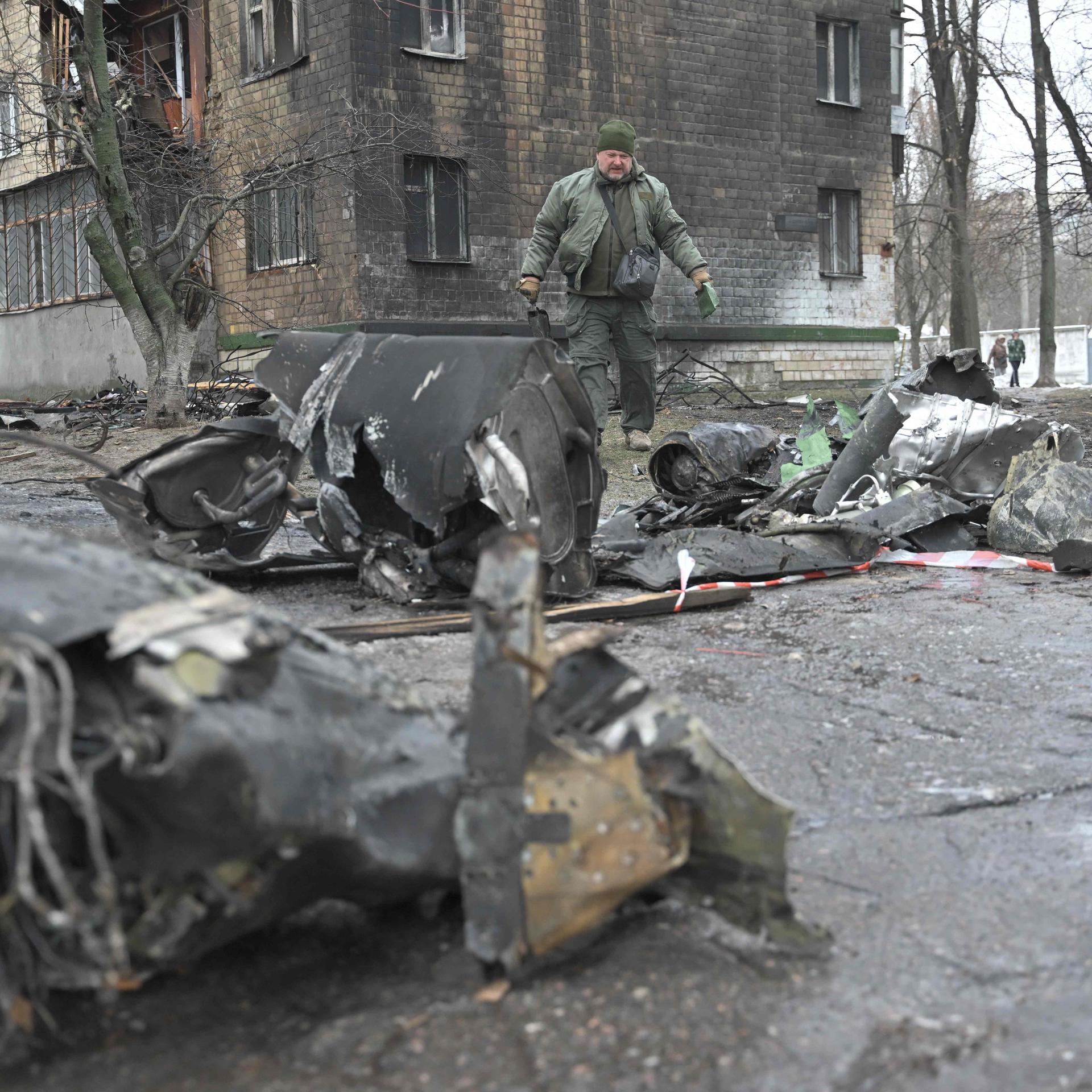 A law enforcement officer stands among the remains of an undetonated rocket next to a residential building following a missile attack in Kyiv on January 23, 2024. Dozens of people were injured and least four killed after a wave of Russian missiles targeted Kyiv and other cities across Ukraine, setting residential buildings ablaze and reducing others to rubble. (Photo by Genya SAVILOV / AFP)