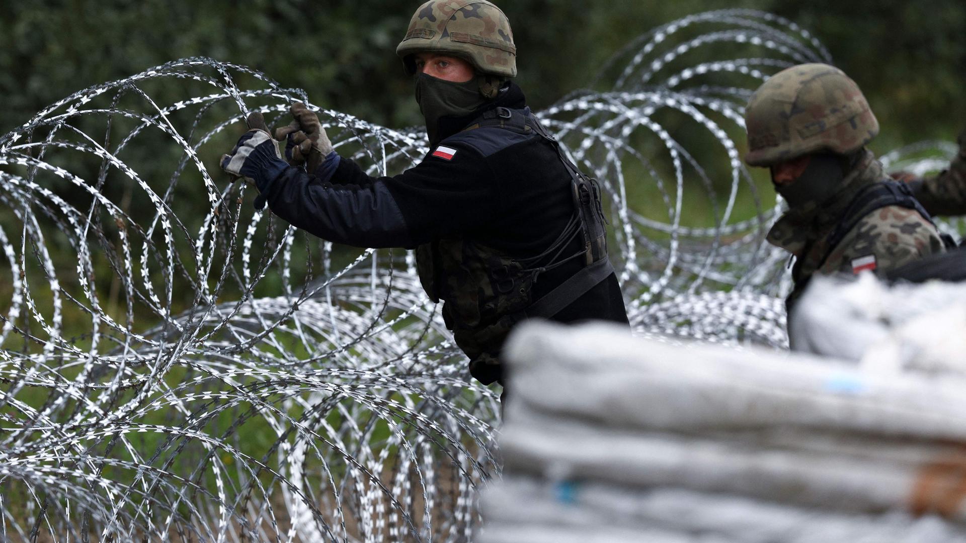 Polish soldiers construct a barbed wire fence on the border with Belarus in Zubrzyca Wielka near Bialystok, eastern Poland on August 26, 202