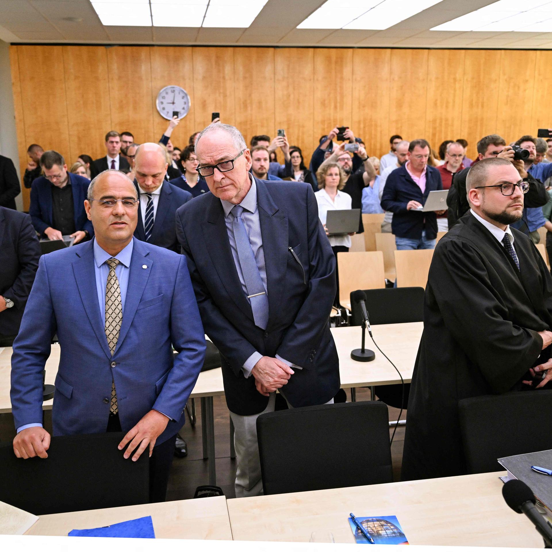 Peter Boehringer (L) and Roman Reusch (C), both members of Germany's far-right Alternative for Germany (AfD) party, and their lawywer Christian Conrad (R) wait for the verdict of the trial at the Higher Administrative Court in Muenster, western Germany on May 13, 2024.
