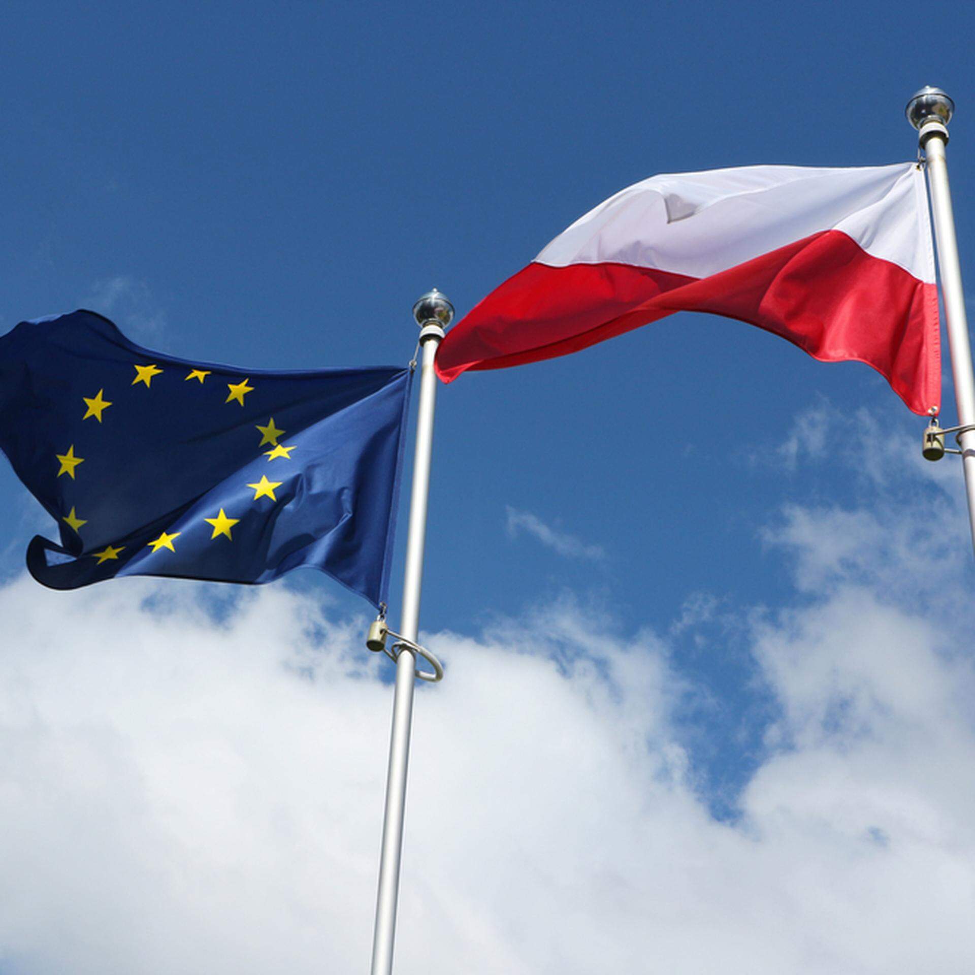 Poland flag and European Union flag on a background of blue sky with clouds