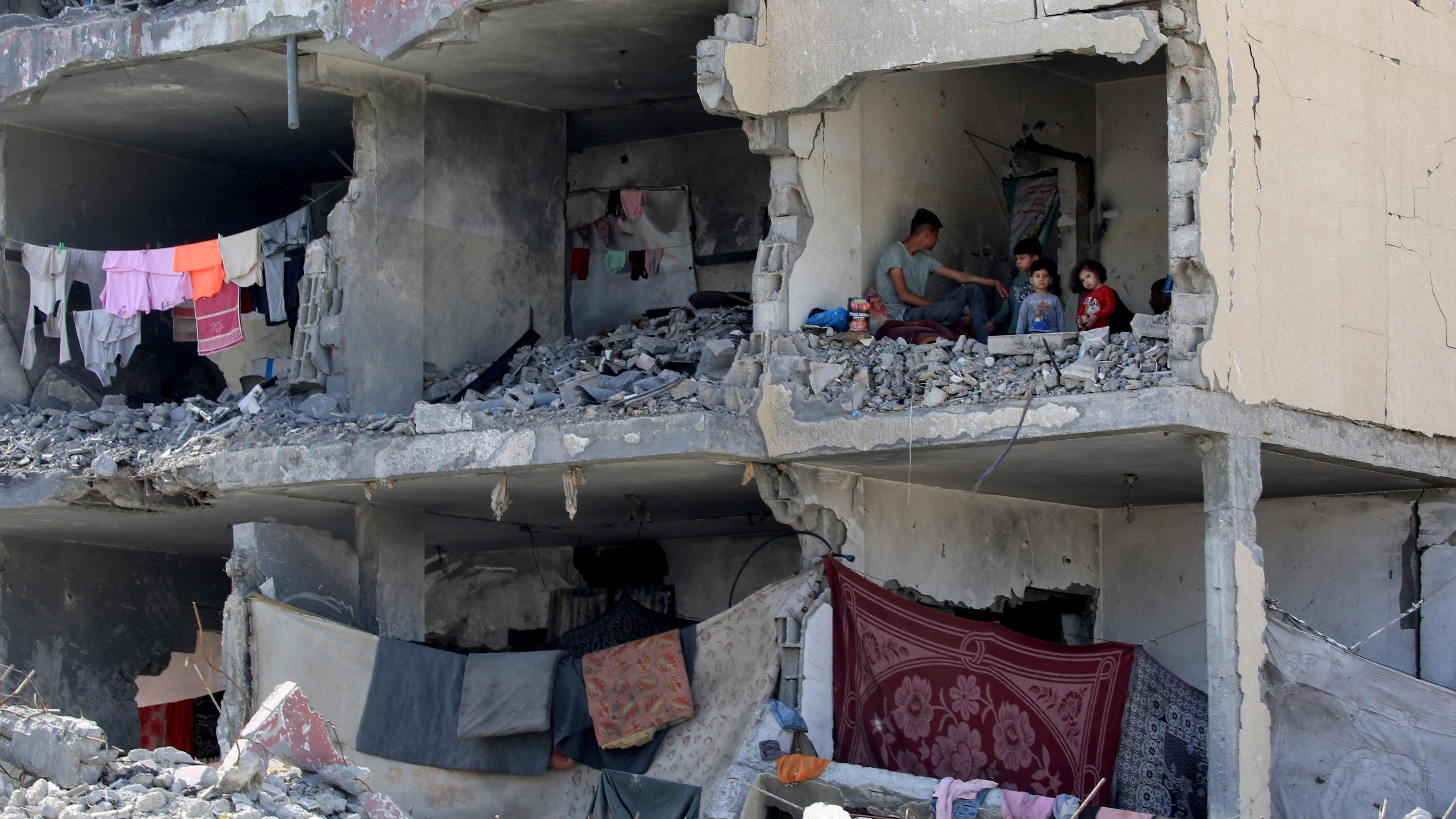 A Palestinian man and his children sit in a destroyed room following the targeting or a residential building by an Israeli airstrike in Rafah in the southern Gaza Strip on May 22, 2024